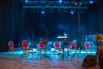 Music stands, microphones, musical instruments and chairs at a concert stage