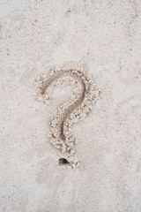 Fototapeta na wymiar Question mark sign drawn on beach sand.