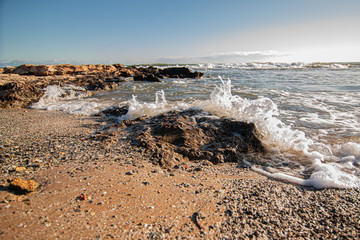 Olas chocando contra roca en playa.