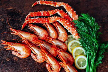 On the table are shrimp, crab, lemon and herbs. Table of reddish color.