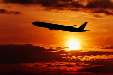 Fototapeta na wymiar Airplane In The Sky At Sunset. Travel background with passenger plane.