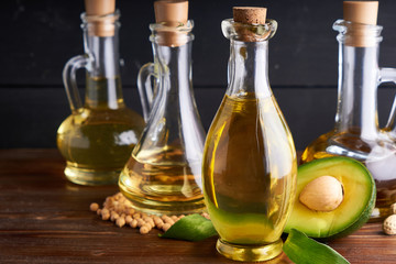Healthy vegetable oils in glass bottles. Avocado oil, chickpea oil, linseed oil, peanut oil, almond oil. Dark background