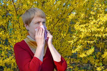 Woman suffers from allergies among yellow flowers foraging