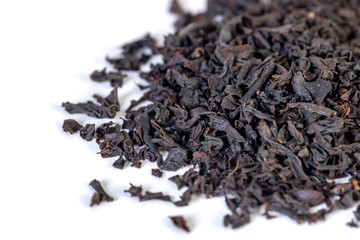 A pile of dried black tea leaves on a white background.