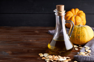 Healthy Pumpkin oil in glass bottle. Dark wooden background Copy space
