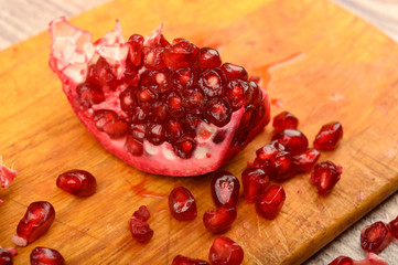 Pieces of ripe juicy pomegranate and pomegranate seeds on a wooden Board on a wooden background....