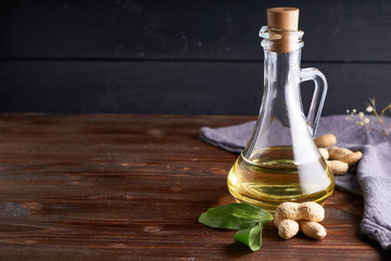 Fototapeta na wymiar Healthy Peanut oil in glass bottle. Dark wooden background Copy space