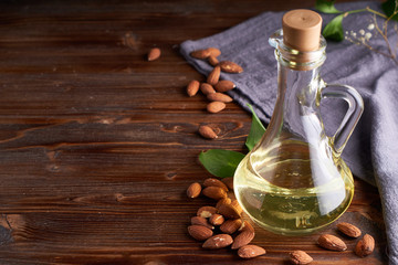 Obraz na płótnie Canvas Healthy Almond oil in glass bottle. Dark wooden background Copy space