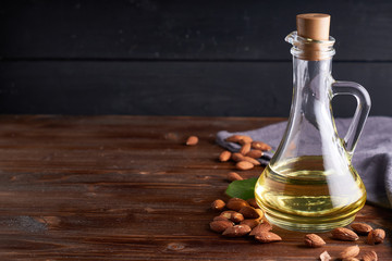 Obraz na płótnie Canvas Useful Almond oil in glass bottles. Dark wooden background Copyspace