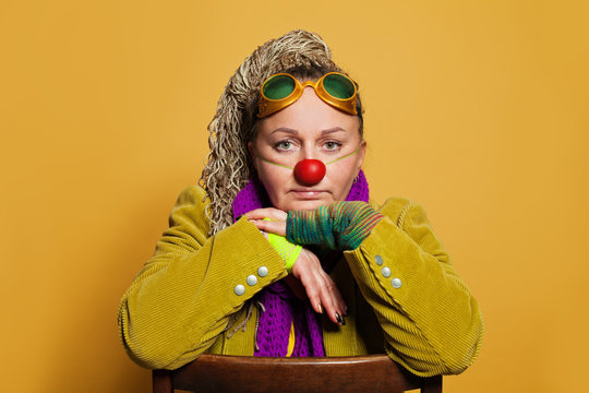 Mature woman psychologist in clown costume for performance in childrens hospis on yellow background. Real people portrait