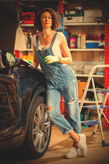 Fototapeta na wymiar pretty woman mechanic in blue denim overalls studies repair guide