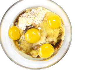 Corn and rice flour, coconut sugar, four eggs in the transparent plate. Making a cake. Mixing the dough. White background. Copy space. Place for text and design. Top view. Flat lay. Gluten-free recipe