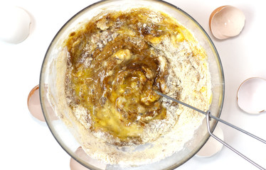 Corn and rice flour, coconut sugar, four eggs in the transparent plate. Making a cake. Mixing the dough. White background. Copy space. Place for text and design. Top view. Flat lay. Gluten-free recipe