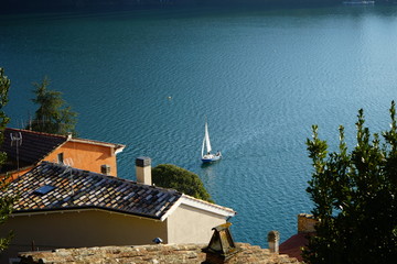 Sail boat approaching tipical lakeside village