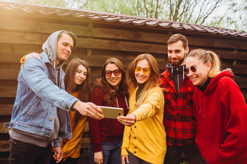 Funny selfie with friends. company of cheerful friends making selfie and smiling while standing outdoors. people wear red and yellow jumpers. young people resting in nature, talking and laughing