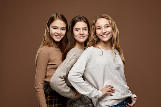 Cute happy girls embrassing, on brown background