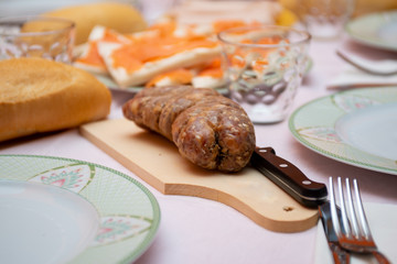 salami with knife on cutter board on laid table