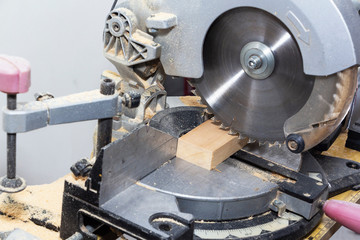 A miter saw making a compound cut through construction lumber.