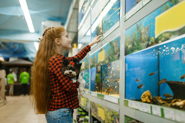 Girl looking on fishes in aquarium, pet store