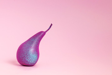 Bright purple pear close-up on a pink background. Horizontal photo, lots of space for text on the right. Creative minimalistic concept.