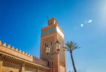 Tower of mosque minaret at medina quarter of Marrakesh, Morocco. There are walls and palms. It is a...