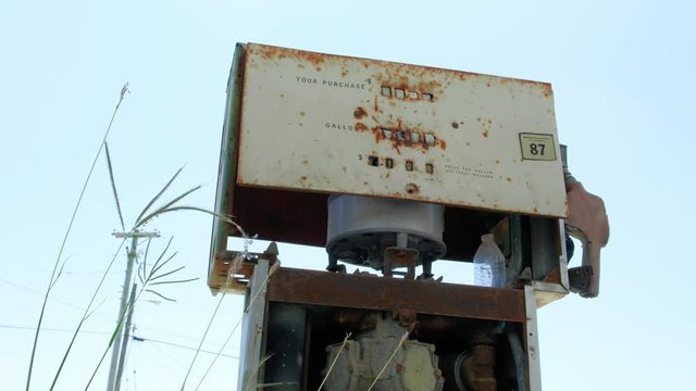 Abandoned, deplorable looking old gas pump against blue sky, zoom in shot