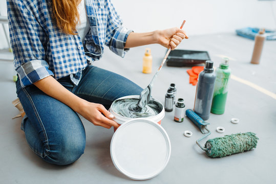Female house painter mixes paints in pail