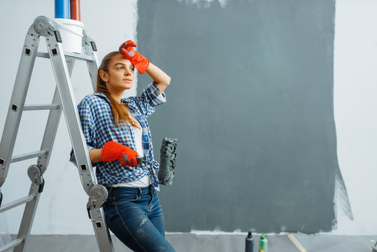 Tired Female House Painter With Roller Paints Wall