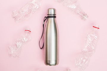 reusable metal water bottle and crumpled plastic bottles isolated on pink background, top view