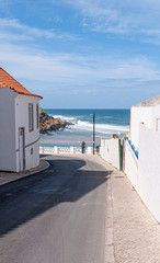 Sea view with one man leaning against a white wall, looking out to the Atlantic ocean. Taken on a sunny day in Colares, Portugal.