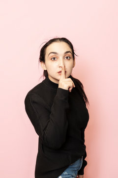 Keep quiet sign. Portrait of a beautiful woman in casual clothing showing hand gesture keep silence. Tss, Shh