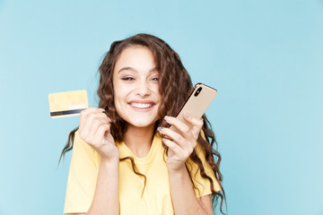 Surprised happy woman with phone and yellow credit card holding it isolated