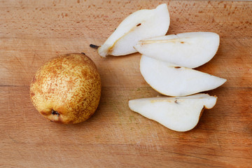 Peeled and sliced pear on a wooden board.