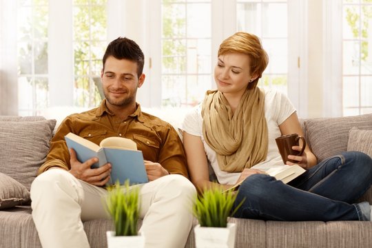 Young couple reading book on sofa