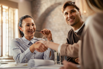 Happy Asian financial advisor greeting with her clients in the office.