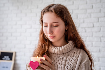 Cute young woman holding a candle with a heart shape
