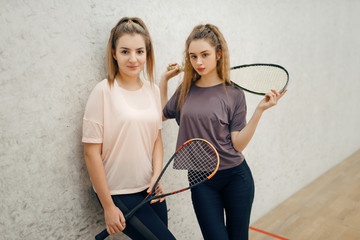 Two female players poses with squash rackets