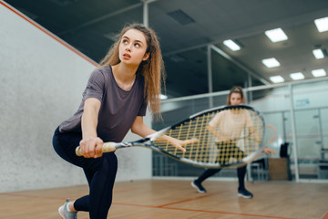 Two players with squash racket playing on court