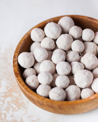 Cranberries in powdered sugar in a wooden plate close-up.