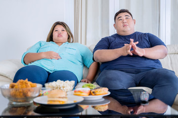 Obraz na płótnie Canvas Portrait of fat couple watching tv with boredom