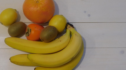 Tropical fruits of various sizes on a white wooden table background 