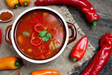 Homemade goulash soup in a stone dish surrounded by colorful peppers
