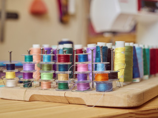 Close-up of multi-colored spools of thread on a wooden stand in a studio