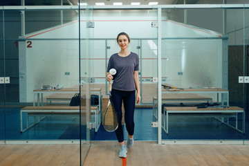 Female player with squash racket in locker room