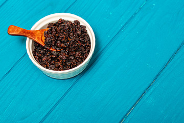 Dried barberry in a spoon on an aquamarine background. Spice.