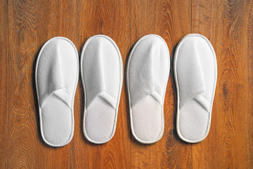 Top view two pairs of new soft white slipper in the hotel on wooden floor. Four white slipper, Isolated on wooden floor. Top view.                               