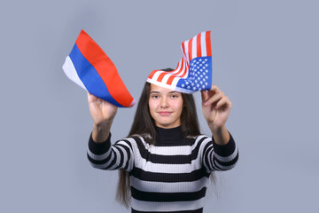 girl holding in hands flags of usa and russia