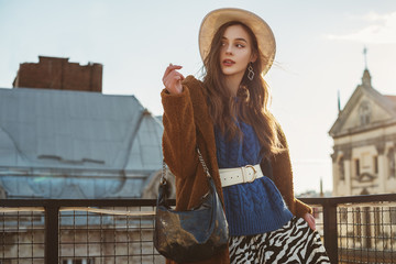 Fashionable  woman wearing trendy brown faux fur coat, blue knitted sweater, wide leather belt,...