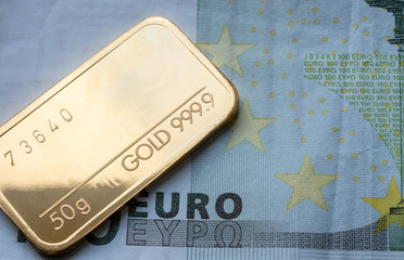 Minted gold bar weighing 50 grams 999.9, fineness against the background of euro banknote.