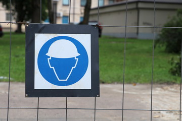 Fototapeta na wymiar Safety helmet must be worn.Construction sign on the metal fence